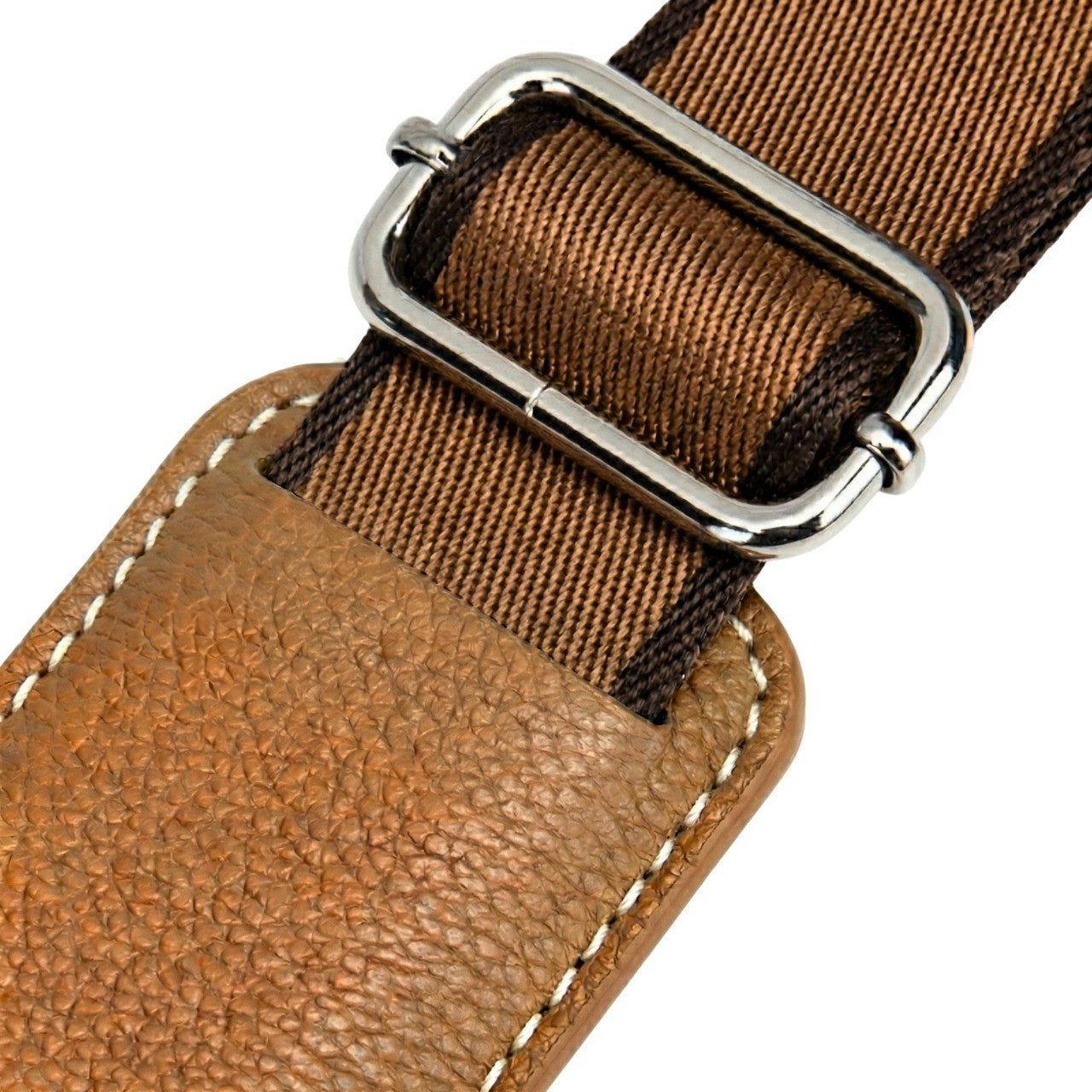 Close-up of a VUOTÍGA bags leather shoulder strap with a metal buckle on a white background